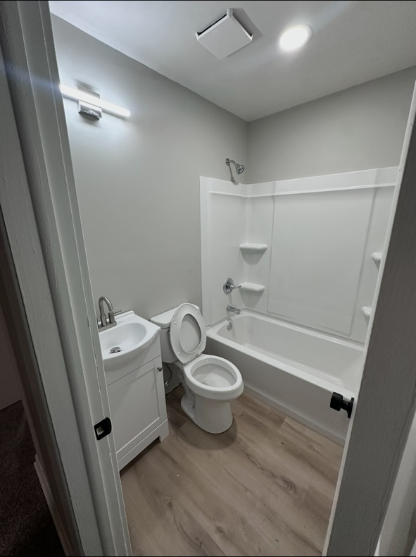 Bathroom after renovation with gray walls, white tub surround and light wood-look flooring
