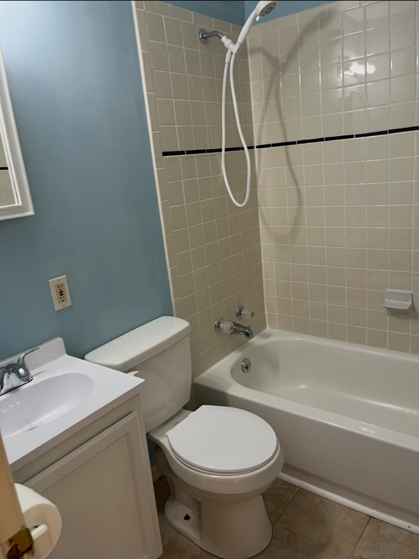 Bathroom before renovation with blue walls, beige shower tile and older flooring