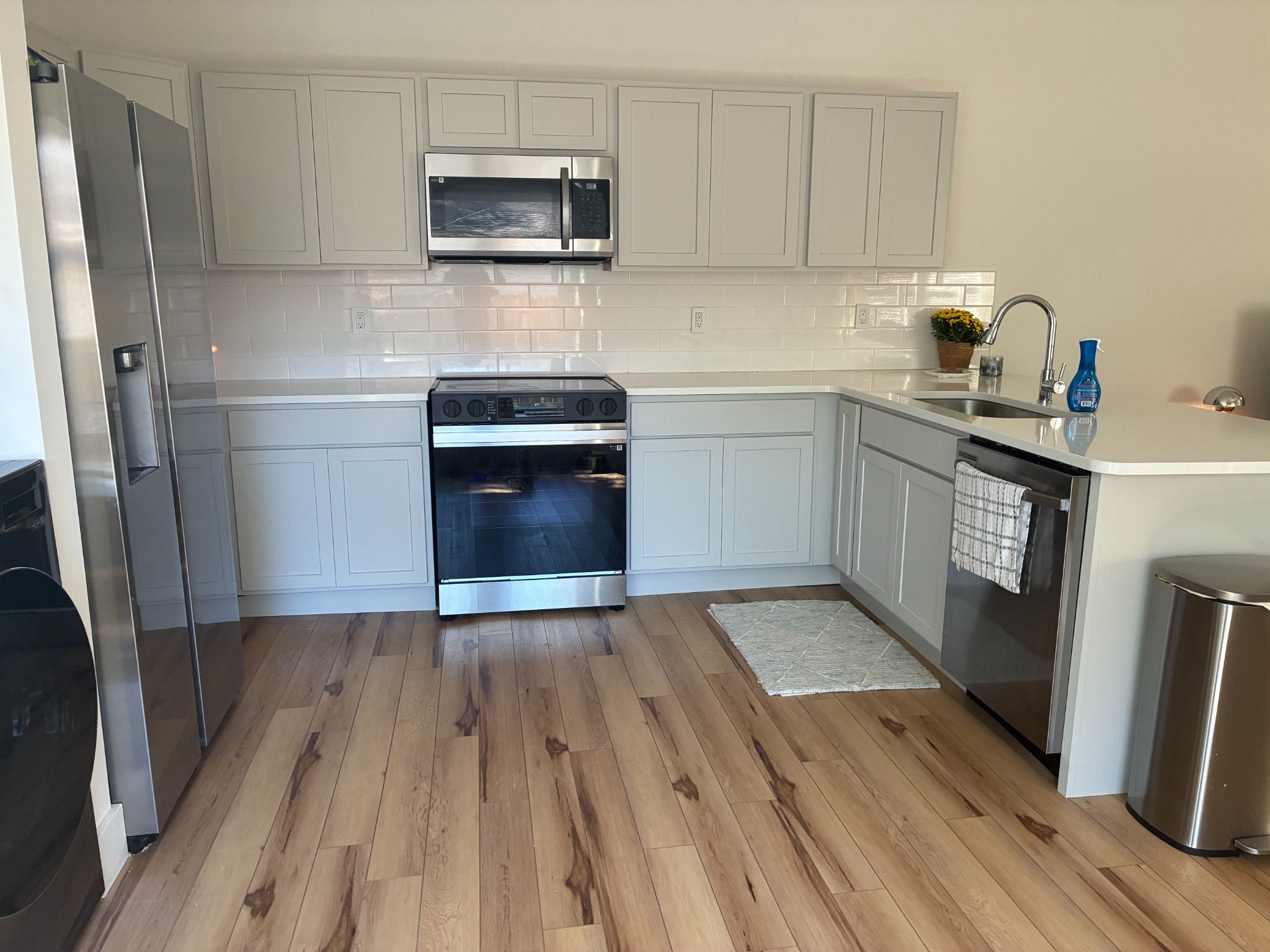 Remodeled rental kitchen with light gray cabinets, quartzite countertops, white backsplash and stainless steel appliances
