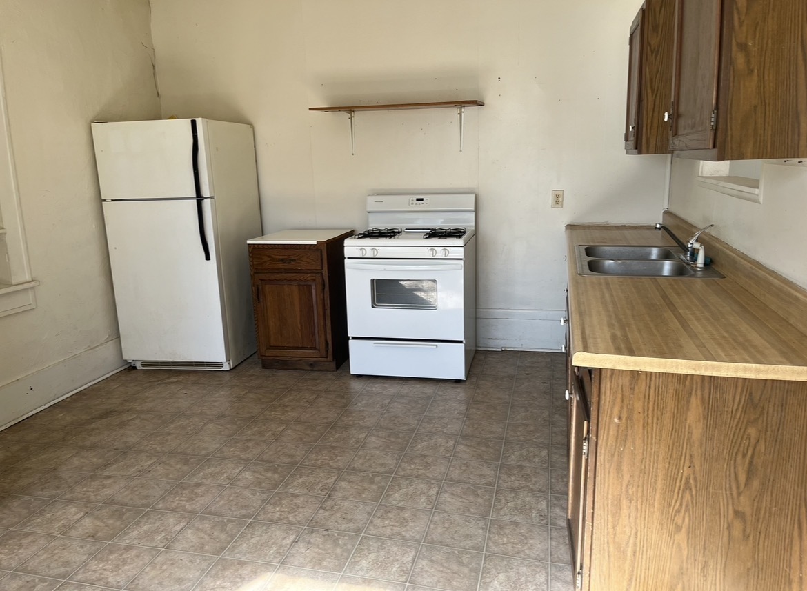 Rental kitchen before remodeling with brown cabinets, laminate countertops and white appliances
